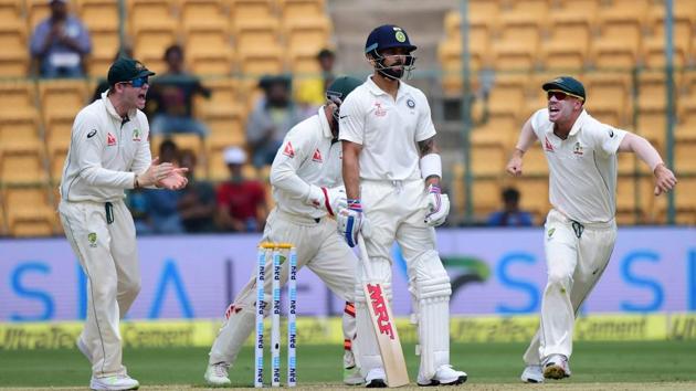 India's Virat Kohli looks on as Australian cricketers celebrate his dismissal during the first day of the second test match at Chinnaswamy Stadium in Bengaluru.(PTI)
