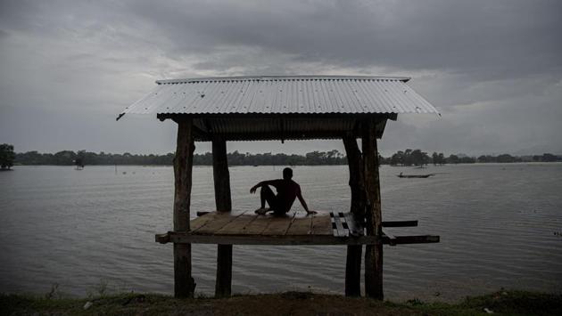 A man sits in a shack next to flood waters in Morigaon district on Jun 26. The monsoon remains crucial for the yield of rice, wheat, sugarcane and oilseeds in a country where farming accounts for about 15% of the economy but employs more than half of its people, a HT report noted. (Anupam Nath / AP)