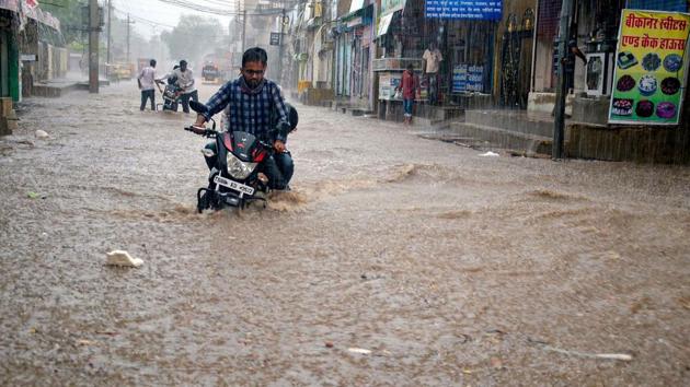 A motorist moves through a waterlogged street during heavy rain in Rajasthan’s Sikar district on June 26. Several areas in Rajasthan, Haryana and Uttar Pradesh have reported locust attacks with the onset of the southwest monsoon. The humid weather and intermittent rainfall provide a fertile ground to the pink immature adults to multiply very rapidly. (PTI)
