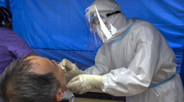 A worker wearing a protective suit swabs a man's throat for a coronavirus test at a community health clinic in Beijing.(AP)