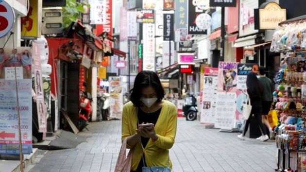A woman wearing a mask looks at her mobile phone amid social distancing measures to avoid the spread of the novel coronavirus, in Myeongdong shopping district in Seoul, South Korea on May 28, 2020.(Reuters File Photo)