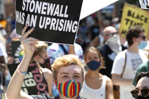 A person holds up a sign referencing the Stonewall Inn, a gay bar that was the site of a series of spontaneous, violent demonstrations by members of the gay (LGBT) community in response to a police raid that began in the early morning hours of June 28, 1969, during a queer liberation march for Black Lives Matter and against police brutality, Sunday, June 28, 2020, in New York, as marchers celebrated the 50th anniversary of the gay rights movement. \ (AP)