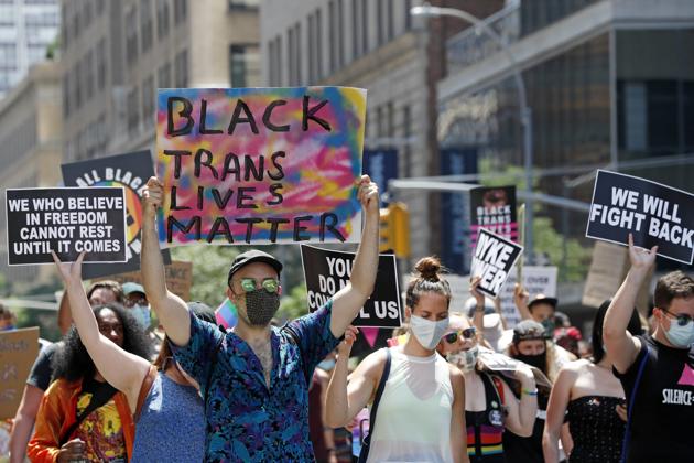 People hold signs as they participate in a queer liberation march for Black Lives Matter and against police brutality, Sunday, June 28, 2020, in Lower Manhattan in New York. (AP)