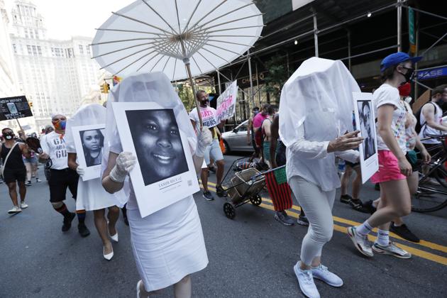 A participant holds a portrait of Tamir Rice, a 12-year old Black boy who was killed in Cleveland, Ohio by a white police officer, during a queer liberation march for Black Lives Matter and against police brutality, Sunday, June 28, 2020, in New York. The march was held to commemorate the 50th anniversary of the Pride movement after New York's massive Pride march was cancelled due to concerns over the spread of coronavirus. (AP)
