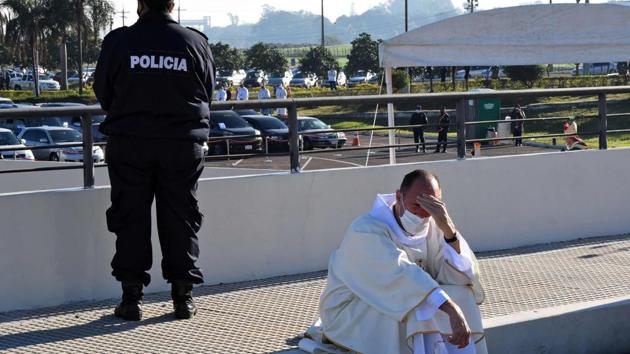 A priest takes a break during a drive-in mass at the Silvio Pettirossi International Airport parking in Luque, near the Paraguayan capital on June 28. The pandemic has altered the nature of our public interactions which are now forced to adapt to distancing norms and mandatory alterations necessitated by the coronavirus for the foreseeable future. (Norberto Duarte / AFP)
