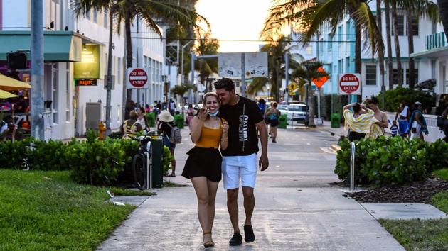 A couple embrace each other as they walk on Ocean Drive in Miami Beach, Florida on June 26. Economies battered by extended lockdowns have forced early easing in several parts of the world. But opening economies is fraught with the risk of renewed outbreaks in multiple US states this week where daily cases soared as people stepped out of confinement. (Chandan Khanna / AFP)