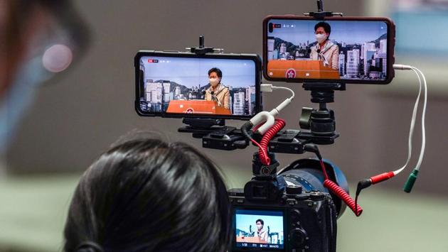 Carrie Lam, Hong Kong's chief executive, is seen on the screens of smartphones live-streaming a news conference on June 30. Lam told the United Nations Human Rights Council in a video message that the law was urgently needed after the city was “traumatized by escalating violence fanned by external forces” during the unrest last year. Lam said the measure wouldn’t impact the city’s judicial independence. (Lam Yik / Bloomberg)