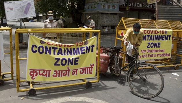 A delivery person pulls a cycle loaded with LPG cylinders past a barricade at a COVID-19 containment zone in New Delhi on June 29. The number of such zones in the national capital stands at 440 as of June 29 after the Delhi government decided to break existing hot spots into smaller clusters for better surveillance and control of the outbreak. (Manvender Vashisht / PTI)