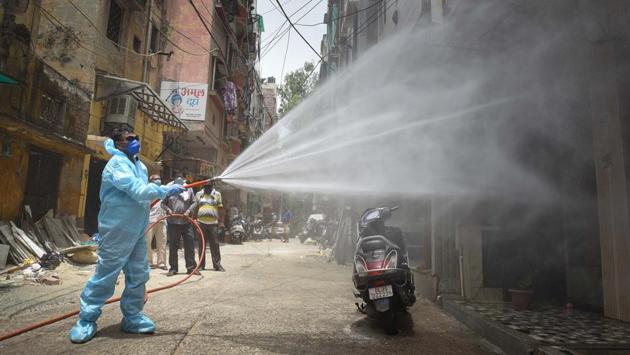 A municipal worker in PPE coveralls sprays disinfectant in an area designated a containment zone in Reghar Pura on June 29. As part of the new delineation strategy, clusters within existing containment zones were made into micro-containment zones. Until June 26, when the new strategy was finalised by the office of the divisional commissioner, Delhi had 280 containment zones. (Sanchit Khanna / HT Photo)