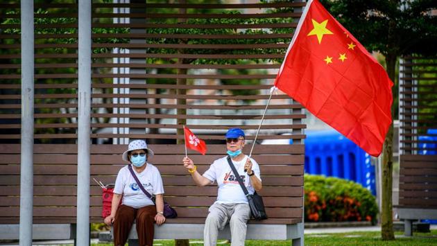 Pro-China supporters display Chinese and Hong Kong flags near the government headquarters in Hong Kong on June 30. Chinese President Xi Jinping has signed an order approving a national security law that will allow authorities to crack down on subversive and secessionist activity in Hong Kong. (Anthony Wallace / AFP)