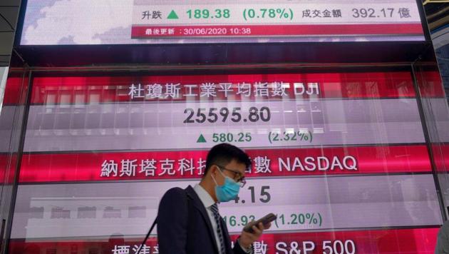 A man wearing a face mask walks past a bank's electronic board showing the Hong Kong share index at Hong Kong Stock Exchange Tuesday, June 30, 2020. (AP photo) A man wearing a face mask walks past a bank's electronic board showing the Hong Kong share index at Hong Kong Stock Exchange Tuesday, June 30, 2020. (AP photo)