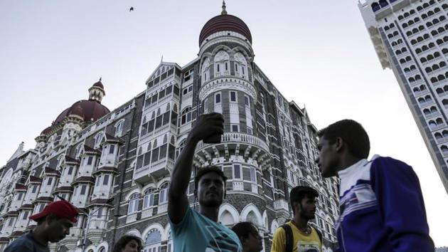 A visitor poses for a photograph outside the Taj Mahal Palace hotel in Mumbai.(Bloomberg File Photo)