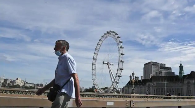 A man wearing a protective mask strolls across a bridge in central London.(AP File)