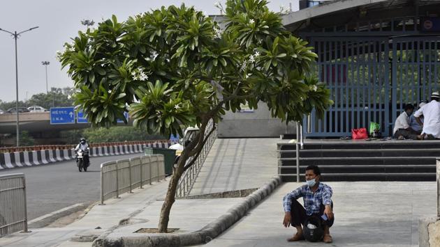 A man takes shelter under the shade of a small tree on a hot summer day next to the closed entrance of a metro station in New Delhi on June 30. Travel restrictions continue in the manner of Unlock 1.0 with metro rail services suspended. Domestic and international flights (under the Vande Bharat exercise) and existing passenger train services will be expanded in a calibrated manner. (Sanjeev Verma / HT Photo)
