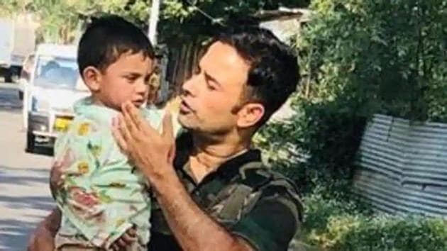 A policeman is seen carrying the three-year-old boy to safety in Sopore on Wednesday. (Twitter/@KashmirPolice) A policeman is seen carrying the three-year-old boy to safety in Sopore on Wednesday. (Twitter/@KashmirPolice)