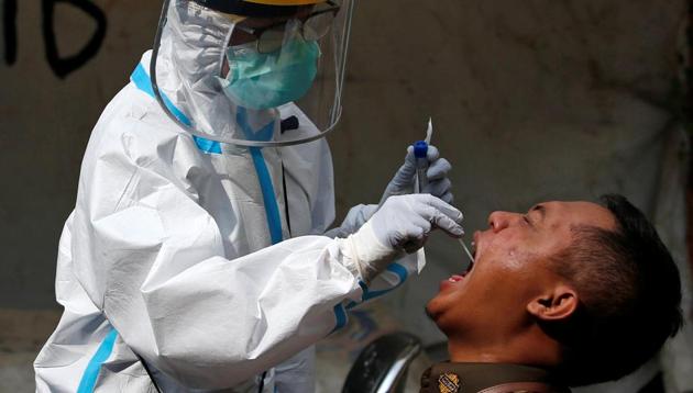 A healthcare worker in protective gear collects a swab sample to be tested for the coronavirus disease (COVID-19) from a civil servant at a traditional textile market in Jakarta, Indonesia, July 2, 2020. REUTERS/Willy Kurniawan (REUTERS)