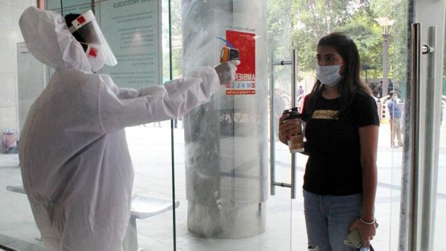 A woman is thermal screened at the entrance of Ambience Mall as it reopens after lockdown, in DLF Phase-3 on July 1. Malls in Gurugram sputtered back to life on July 1, after a three month pause owing to the raging Covid-19 pandemic, which has so far infected 5463 people in Gurugram and killed 92. On Day One of their reopening, however, most malls experienced thin footfall. (Rahul Grover / HT Photo)