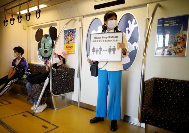 A staff member holds a sign to remind visitors to practice social distancing before the reopening of Tokyo Disneyland along with Tokyo DisneySea, which closed for months due to the coronavirus disease (COVID-19) outbreak, at a Disney Resort line train in Urayasu, east of Tokyo, Japan July 1, 2020. (REUTERS) A staff member holds a sign to remind visitors to practice social distancing before the reopening of Tokyo Disneyland along with Tokyo DisneySea, which closed for months due to the coronavirus disease (COVID-19) outbreak, at a Disney Resort line train in Urayasu, east of Tokyo, Japan July 1, 2020. (REUTERS)