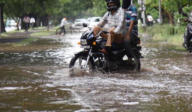 Two wheeler riders struggle to get through a waterlogged spot in Sector 9 after a heavy spell of rain in June this year.(HT Photo)