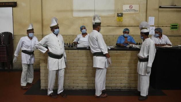 Servers wearing face masks and gloves in addition to their white uniforms and turbans, gather at the billing counter of the Indian Coffee House on College Street in Kolkata on July 2. The authorities reopened the eatery after holding talks with the local police station and health department over COVID-19 safety protocols and guidelines. (Samir Jana / HT Photo)