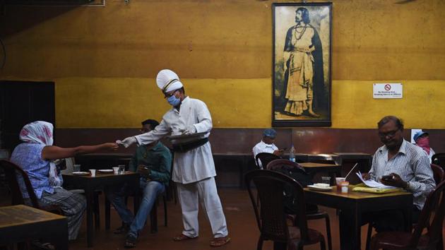 A server wearing a face mask and gloves attends to customers at the Indian Coffee House on College Street in Kolkata on July 2. One of the city’s most loved eateries, the Coffee House had to shut its doors over three months ago because of the coronavirus lockdown imposition in the whole country. (Samir Jana / HT Photo)