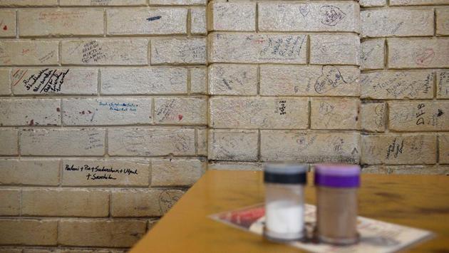 Messages seen scribbled on a wall by a table at the Indian Coffee House in Kolkata, on July 2. The eatery is part of the city’s heritage, having had seen the likes of patrons such as Satyajit Ray, Amartya Sen as well as college students who frequent the place for its reasonable prices and old world charm. (Samir Jana / HT Photo)