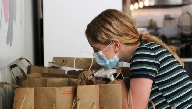 Makenna Hillyard, 13, checks a to-go order at Farley's East in Oakland, California. The cafe temporarily closed during the shelter-in-place but returned first to sell meals-to-go. (REUTERS) Makenna Hillyard, 13, checks a to-go order at Farley's East in Oakland, California. The cafe temporarily closed during the shelter-in-place but returned first to sell meals-to-go. (REUTERS)
