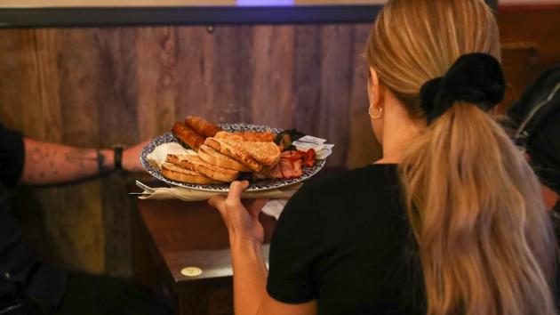 A server carries a fried breakfast at The Moon Under Water pub in London on July 4. Though the easing of the lockdown will be warmly welcomed by many, there are concerns that the British government is being overly hasty in sanctioning the changes, given the country’s still high coronavirus infection and death rates. (Simon Dawson / Bloomberg)