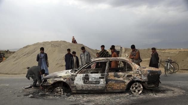 FILE - In this April 9, 2019, file photo, Afghans watch a civilian vehicle burnt after being shot by US forces following an attack near the Bagram Air Base, north of Kabul, Afghanistan.(AP)