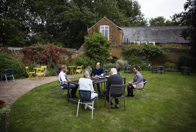 Britain's Prince William, back centre, talks to the landlords Anthony and Jeannette Goodrich, centre foreground, and bar staff in the garden of The Rose and Crown pub in Snettisham, England, Friday July 3, 2020.  (AP) 