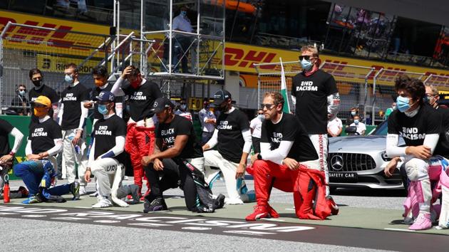 Mercedes' Lewis Hamilton, Ferrari's Sebastian Vettel and the rest of the drivers kneel on the grid.(REUTERS)