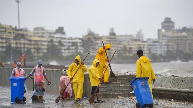 Municipal workers clean garbage washed ashore by waves crashing Marine Drive promenade, during high tide, in Mumbai, Sunday, July 5, 2020. (PTI)