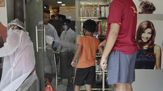 A hairstylist sanitizes a boy before letting him enter a salon in Mumbai, India.(AP)