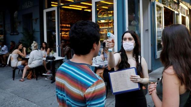 A waitress takes the temperature of customers as they arrive to eat at a restaurant in the Lower East Side neighbourhood of Manhattan, on June 27. (Reuters File Photo) A waitress takes the temperature of customers as they arrive to eat at a restaurant in the Lower East Side neighbourhood of Manhattan, on June 27. (Reuters File Photo)