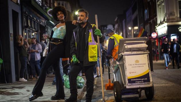 A woman poses with a street cleaner in Soho as late-night drinkers continue into the early hours of Sunday morning as coronavirus lockdown restrictions are eased across England. (AP) A woman poses with a street cleaner in Soho as late-night drinkers continue into the early hours of Sunday morning as coronavirus lockdown restrictions are eased across England. (AP)