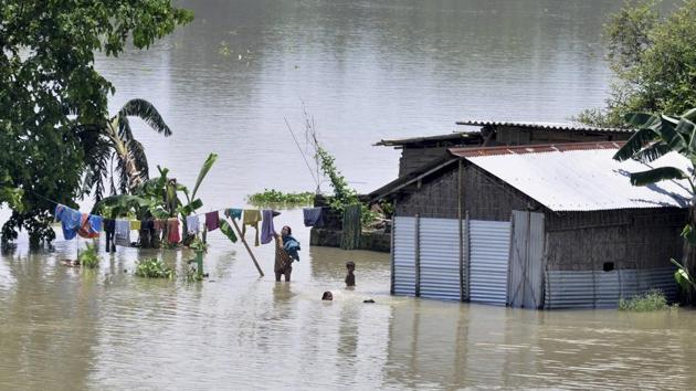 A woman dries clothes as others swim in a flooded area of Morigaon, Assam, July 1. It is time the central and the state governments prepare a long-term plan that goes beyond piecemeal measures like building embankments and dredging to control floods(PTI) A woman dries clothes as others swim in a flooded area of Morigaon, Assam, July 1. It is time the central and the state governments prepare a long-term plan that goes beyond piecemeal measures like building embankments and dredging to control floods(PTI)