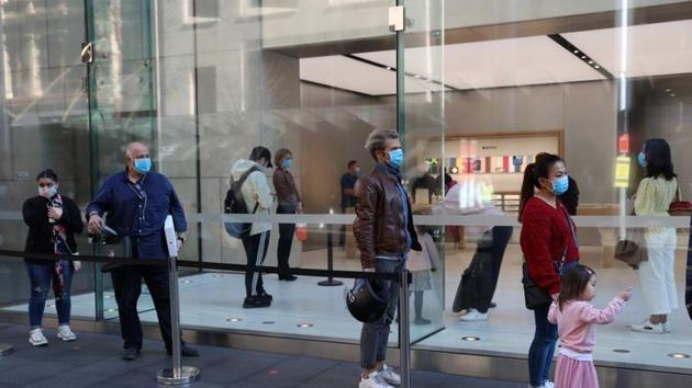 People wearing protective face masks practice social distancing while waiting to enter an Apple store on the first day of New South Wales' further eased coronavirus disease (Covid-19) restrictions in Sydney, Australia on July 1, 2020.(REUTERS)