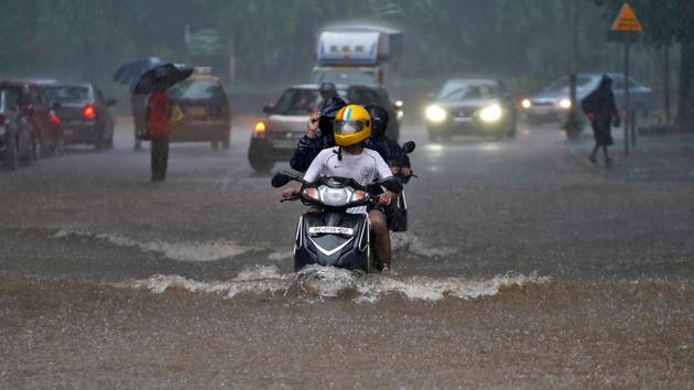 People ride their scooters through a water-logged road during heavy rains in Mumbai, India. (REUTERS) People ride their scooters through a water-logged road during heavy rains in Mumbai, India. (REUTERS)
