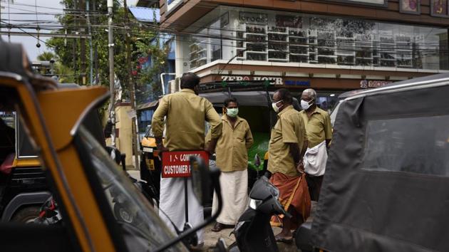 Autorickshaw drivers wearing masks as a precaution against the coronavirus chat as they wait for customers in Kochi, Kerala state, India.(AP)