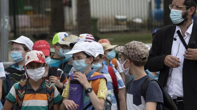Israeli school children wear face masks to help prevent the spread of the coronavirus as they walk in Tel Aviv, Israel.(AP)