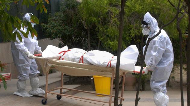 Medics wearing PPE kits carry the body of a person who died of COVID-19 at a district hospital, in Noida. (PTI) Medics wearing PPE kits carry the body of a person who died of COVID-19 at a district hospital, in Noida. (PTI)