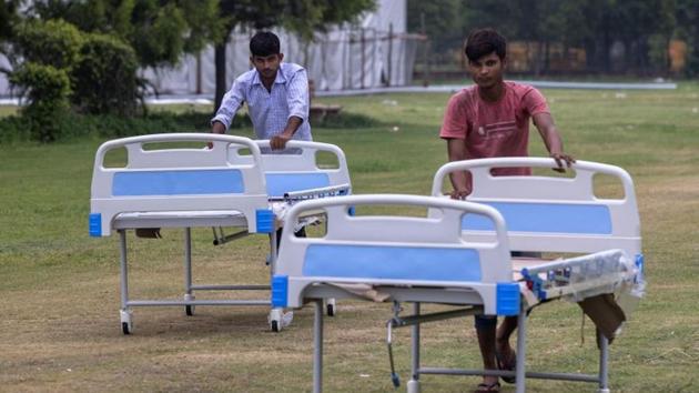 Workers push beds to an under construction High Dependency Unit (HDU) at a coronavirus disease (COVID-19) care centre for patients inside an indoor sports complex, amidst the spread of the disease, in New Delhi. (REUTERS)
