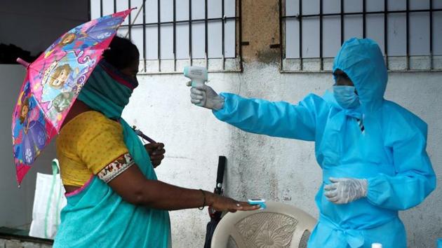A healthcare worker checks the temperature and pulse of a resident during a check-up camp for the coronavirus disease (Covid-19), in Mumbai on July 4, 2020.(REUTERS)