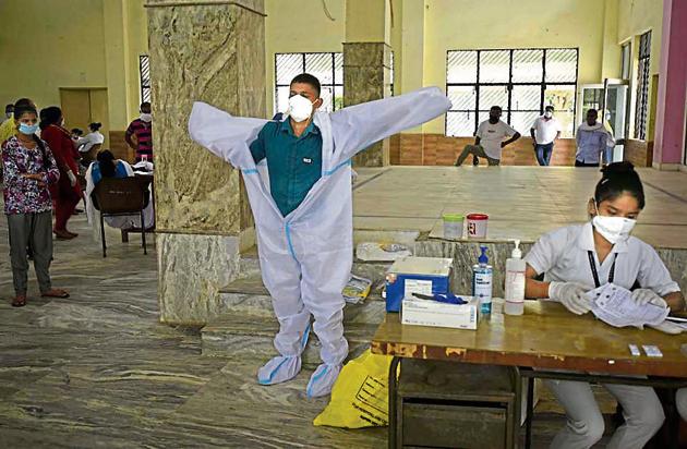 A health worker taking out his personal protective equipment at a community centre in Gurugram (Parveen Kumar/HT) A health worker taking out his personal protective equipment at a community centre in Gurugram (Parveen Kumar/HT)