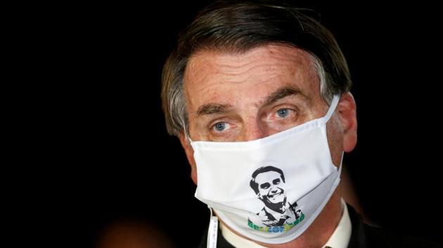Brazil's President Jair Bolsonaro speaks with journalists while wearing a protective face mask as he arrives at Alvorada Palace, amid the coronavirus disease (COVID-19) outbreak, in Brasilia, Brazil.(REUTERS)