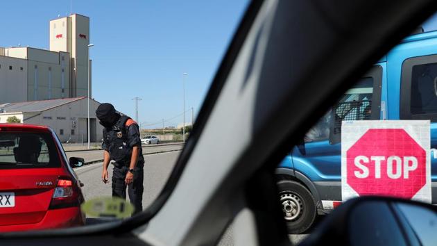 A police officer screens commuters for documents at the entrance of Lleida on July 4 after Catalonia’s government imposed new restrictions to control the coronavirus outbreak. The five-day measure was ordered after cases started to rise from two different outbreaks. (Nacho Doce / REUTERS) A police officer screens commuters for documents at the entrance of Lleida on July 4 after Catalonia’s government imposed new restrictions to control the coronavirus outbreak. The five-day measure was ordered after cases started to rise from two different outbreaks. (Nacho Doce / REUTERS)
