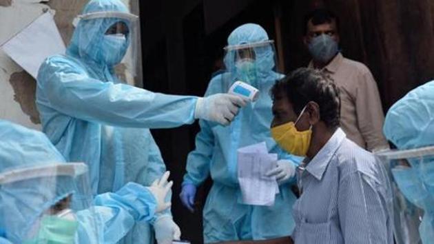File photo: A health care worker checks the temperature of a man.(Satish Bate/HT Photo)