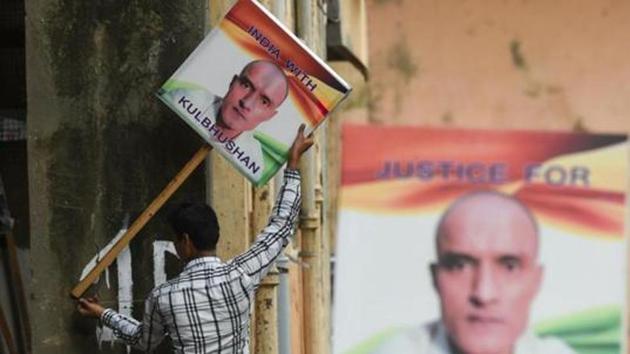 (FILES) In this file photo taken on July 17, 2019, an Indian man holds a placard depicting Kulbhushan Jadhav, an Indian national convicted of spying in Pakistan, in the neighborhood where he grew up, in Mumbai. - Kulbushan Jadhav, at the centre of a world court battle between his native India and Pakistan, is a man of mystery almost certainly unaware of the war of words being fought over him. (Photo by Indranil MUKHERJEE / AFP)(AFP) (FILES) In this file photo taken on July 17, 2019, an Indian man holds a placard depicting Kulbhushan Jadhav, an Indian national convicted of spying in Pakistan, in the neighborhood where he grew up, in Mumbai. - Kulbushan Jadhav, at the centre of a world court battle between his native India and Pakistan, is a man of mystery almost certainly unaware of the war of words being fought over him. (Photo by Indranil MUKHERJEE / AFP)(AFP)