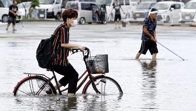 A man on a bicycle makes his way through a flooded road following heavy rains in Kurume, Fukuoka prefecture, southern Japan Wednesday, July 8, 2020.(AP photo)