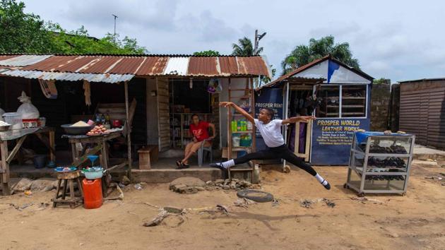 A student of the Leap of Dance Academy, Anthony Madu (R), performs a grand jete leap while his mother Ifoma Madu watches on from her shop in Ajangbadi on July 3. “I feel great, I feel wonderful, I’m very excited,” she told AFP. “When I see him dancing, it gives me joy.” (Benson Ibeabuchi / AFP)